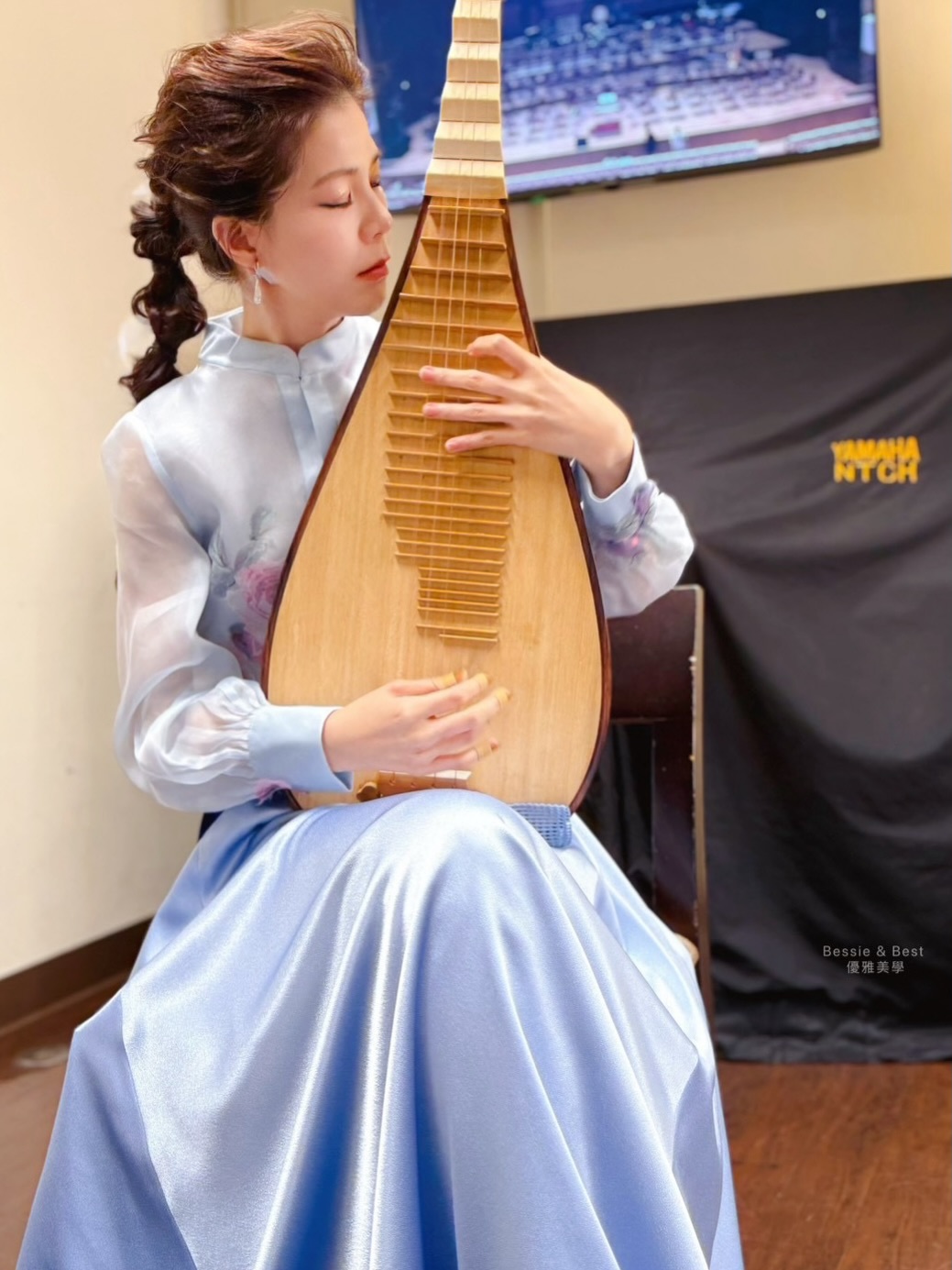 趙怡然首席沉浸彈奏定格・閉目聆韻神態從容，背景國家音樂廳後台監聽螢幕銘刻殿堂專業規格